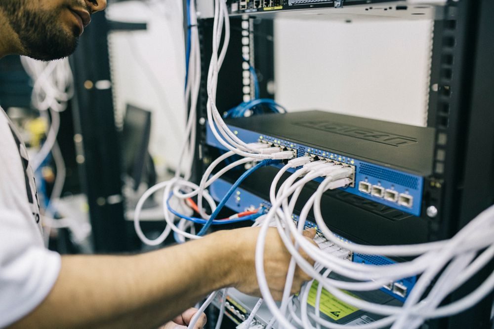 Técnico conectando cables de red en un rack de equipos durante un diagnóstico técnico